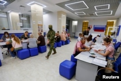 A pro-Russian fighter walks through an Interior Ministry office as Kherson residents apply for Russian passports. A top Ukrainian local official maintained, however, that the number of people applying was "miniscule."