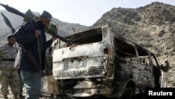 A border policeman stands next to burnt vehicles belonging to a team of Afghan deminers who were kiddnapped by the Taliban in Momand Dara.