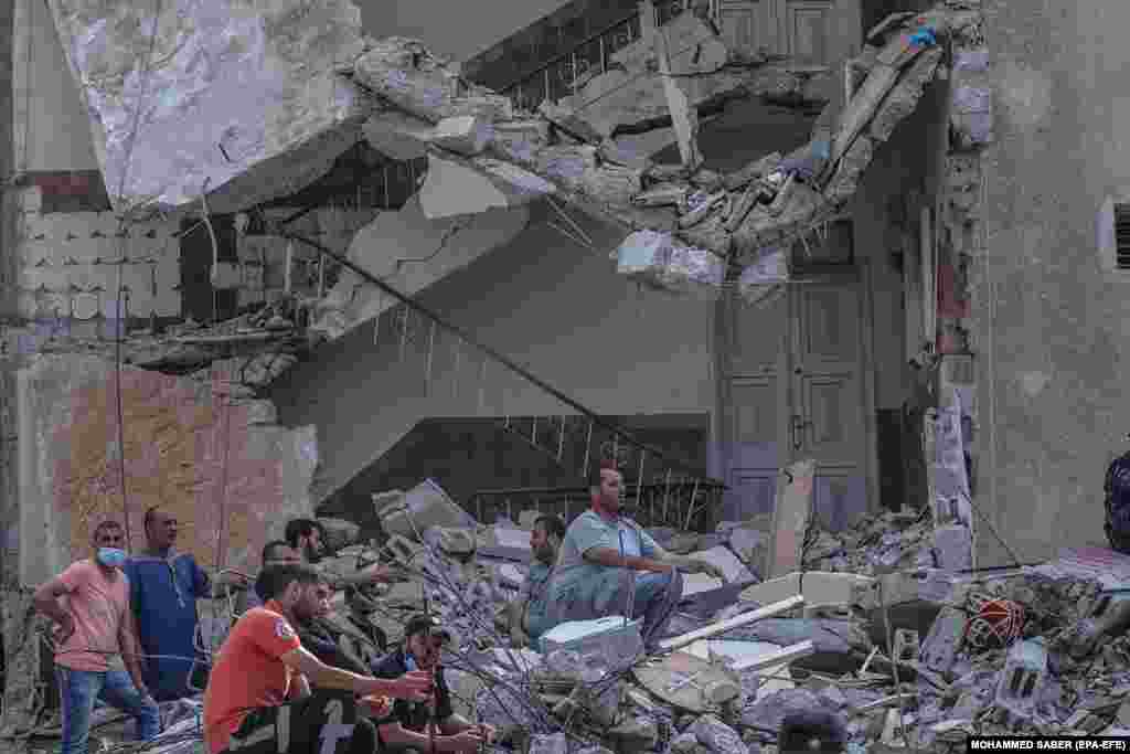 Палестинские спасатели ищут людей между завалами разрушенных домов после авиаудара Израиля по сектору Газа, 16 мая 2021