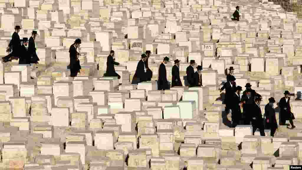 Ultra-Orthodox Jewish men walk between graves before the funeral of Rabbi Abraham Haim Roth, spiritual leader of the Shomrei Emunim Hasidic dynasty, in Jerusalem on August 23.&nbsp; (REUTERS/Baz Ratner)