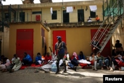 Oamenii așteaptă lângă un centru pentru migranți din Ceuta, la 3 august 2026.