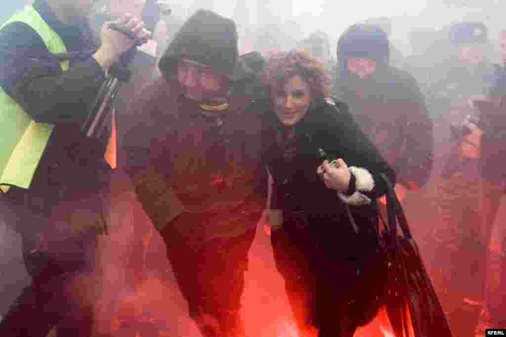 Это не молодой человек выводит из задымления свою девушку, а сотрудник милиции в штатском задерживает активистку оппозиции