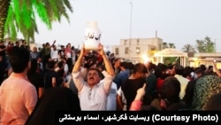 People protest water shortage in Borazjan in southern Iran. The man in the foreground holds an empty jar with the slogan, "We don't have water".