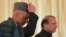 Visiting Afghan President Hamid Karzai (left) is flanked by Pakistani Prime Minister Nawaz Sharif as he adjusts his cap in Islamabad on August 26.