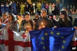 Демонстранты с флагами Грузии и ЕС и со свечами стоят перед церковью Святого Георгия в Кашвети во время протеста оппозиции против «российского закона» в центре Тбилиси. Грузия, 3 мая 2024 года