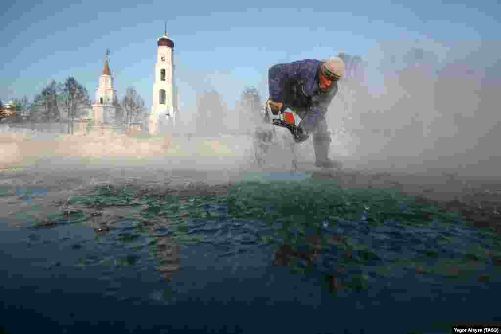 Мужчина вырезает лед на замерзшей реке Сумка в Раифском монастыре в Татарстане, чтобы подготовить прорубь для верующих, которые искупаются в ледяной воде во время празднования Крещения. (ТАСС/Егор Алеев)