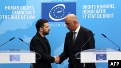 Ukrainian President Volodymyr Zelenskyy and Council of Europe Secretary-General Alain Berset shake hands after the signing of an agreement for establishing a special tribunal to try top officials responsible for Russia's invasion of Ukraine. 