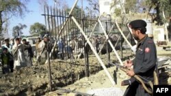 FILE: Afghans watch as a Pakistani paramilitary supervise iron fence installation at the northwestern Torkham border crossing.