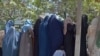 Burqa-clad women who fled their homes ahead of the Taliban&#39;s advance in northern Afghanistan gather to receive aid in a Kabul park on August 13.