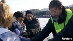 Chinese artist Ai Weiwei (R) helps an Afghan migrant as he arrives with other refugees and migrants on a raft on the Greek island of Lesbos on January 25.