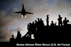 US military mechanics watch as a US Lancer bomber flies overhead at Andersen Air Force Base in Guam in May 2020.