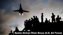 US military mechanics watch as a US Lancer bomber flies overhead at Andersen Air Force Base in Guam in May 2020.
