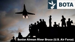 Mekanikët ushtarakë amerikanë shikojnë teksa një bombardues amerikan fluturon sipër bazës ajrore Andersen në Guam, në maj 2020.