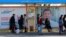 People wait for a bus in front of election campaign posters at a bus stop in the Kyrgyz capital, Bishkek. The country goes to the polls to elect a new president on October 15. 