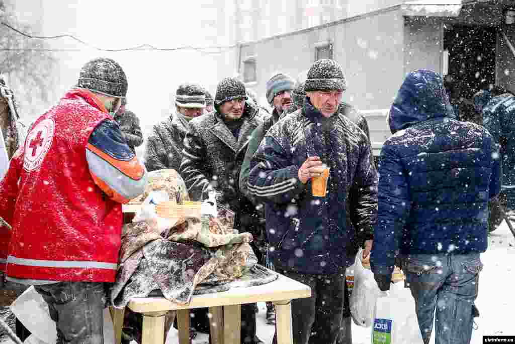 Люди стоять у черзі за порцією гарячої їжі на території мобільного пункту обігріву в районі Малого ринку, Запоріжжя, 6 січня 2017 року