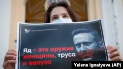 Демонстрант со транспарент на кој пишува „отров е оружје на жена, кукавица и евнух!“ за време на собирот за поддршка на рускиот опозициски лидер Алексеј Навални во центарот на Санкт Петербург, 20.08.2002.