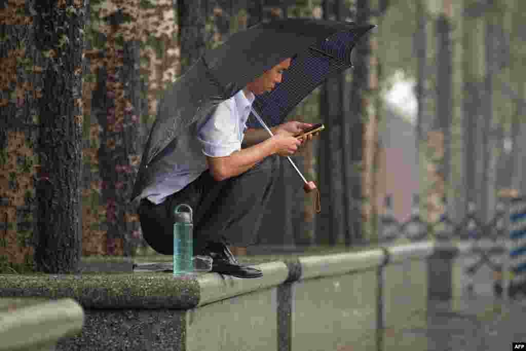 A man shelters beneath an umbrella during rainfall in Beijing.