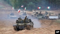 Military vehicles and tanks from Poland, Italy, Canada, and United States take part in NATO military exercises at a training ground in Latvia in September 2021.
