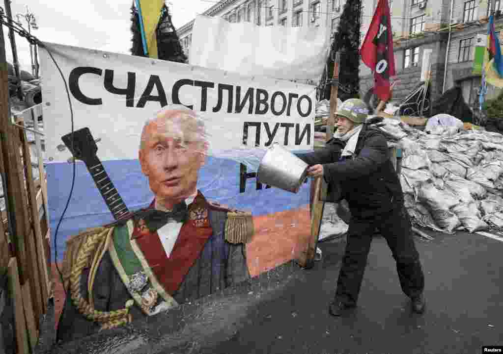 A pro-European-integration demonstrator washes a banner with an image of Russian President Vladimir Putin near a barricade on Independence Square, where the supporters are holding a rally, in Kyiv. (Reuters/Gleb Garanich)