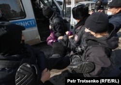 Полиция қызметкерлері митинг өтіп жатқан жерде ұстаған адамды көлікке күштеп салып жатыр. Алматы, 28 ақпан 2021 ж.