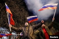 Pro-Russia activists in the occupied Ukrainian city of Donetsk react on the street as fireworks explode in the sky after Putin signed a decree recognizing two Russia-backed separatist entities in eastern Ukraine as independent states.