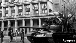 Manifestanți care au luat controlul unui tanc, în miezul zilei de 22 Decembrie 1989, în București, pe Calea Victoriei, lângă Cercul Militar Național. Sunt salutați de trecători. Foto: Agerpres 