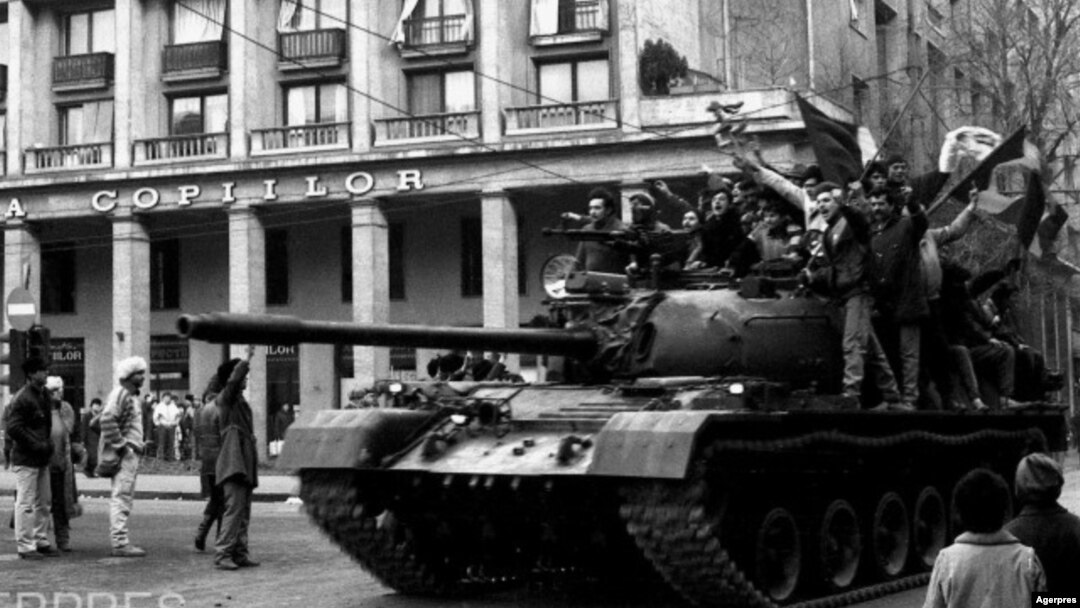 Manifestanți care au luat controlul unui tanc, în miezul zilei de 22 Decembrie 1989, în București, pe Calea Victoriei, lângă Cercul Militar Național. Sunt salutați de trecători. Foto: Agerpres 