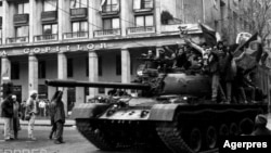 Manifestanți care au luat controlul unui tanc, în miezul zilei de 22 Decembrie 1989, în București, pe Calea Victoriei, lângă Cercul Militar Național. Sunt salutați de trecători. Foto: Agerpres 