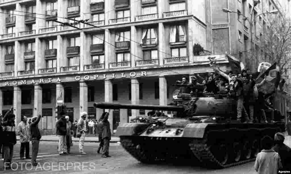 București, 22 decembrie 1989. După fuga lui Nicolae Ceaușescu, o serie întreagă de ofițeri de Armată și Securitate s-au perindat în fața camerelor de luat vederi de la televiziunea publică ordonându-le subordonaților să înceteze orice act de agresiune față de manifestanți. Un ordin similar, de încetare a focului, fusese dat în cursul dimineații de gen. Victor Atanasie Stănculescu, din clădirea Comitetului Central. Acesta participase și a fost ulterior condamnat pentru represiunea de la Timișoara, dar a înțeles că răsturnarea de regim este inevitabilă. Va fi primul ministru al Apărării, dar a fost repede înlocuit de gen. Nicolae Militaru, în care Ion Iliescu, președintele Frontului Salvării Naționale, avea mai multă încredere. Aici un tanc condus de soldații care fraternizaseră cu demonstranții în zona Cercului Militar.&nbsp;