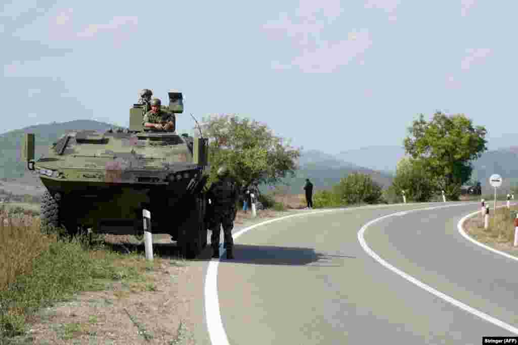 Serbian Army soldiers stand guard by their armored vehicle in the village of Rudnica, near the southern Serbian town of Raska, on September 27. On September 26, Serbian Defense Minister Nebojsa Stefanovic visited troops at two military bases near the Kosovo border, accompanied by Russia&#39;s ambassador to Serbia.