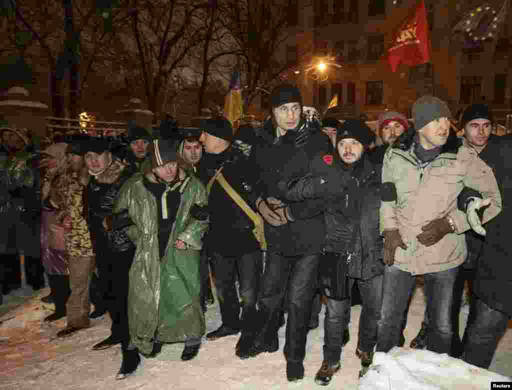 Лідер партії УДАР Віталій Кличко (третій праворуч) поряд із мітингувальниками блокують вулицю біля адміністрації президента, 10 грудня 2013 року