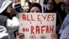 Një grua duke e mbajtur mbishkrimin "Të gjithë sytë në Rafah".