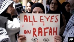 Një grua duke e mbajtur mbishkrimin "Të gjithë sytë në Rafah".