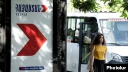 Armenia - A woman walks past a campaign billboard of the opposition Hayastan alliance in Yerevan, May 25, 2021.