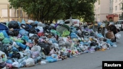 People stand next to a pile of trash in Lviv on June 19.