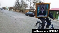 Tigirli prezident G.Berdimuhamedowyň suratyny alyp barýar, Türkmenistan 