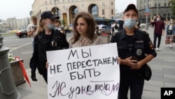 A moszkvai rendőrség bevisz egy "Nem szűnünk meg újságírónak lenni" feliratot tartó tüntetőt, 2021. augusztus 21-én. 
