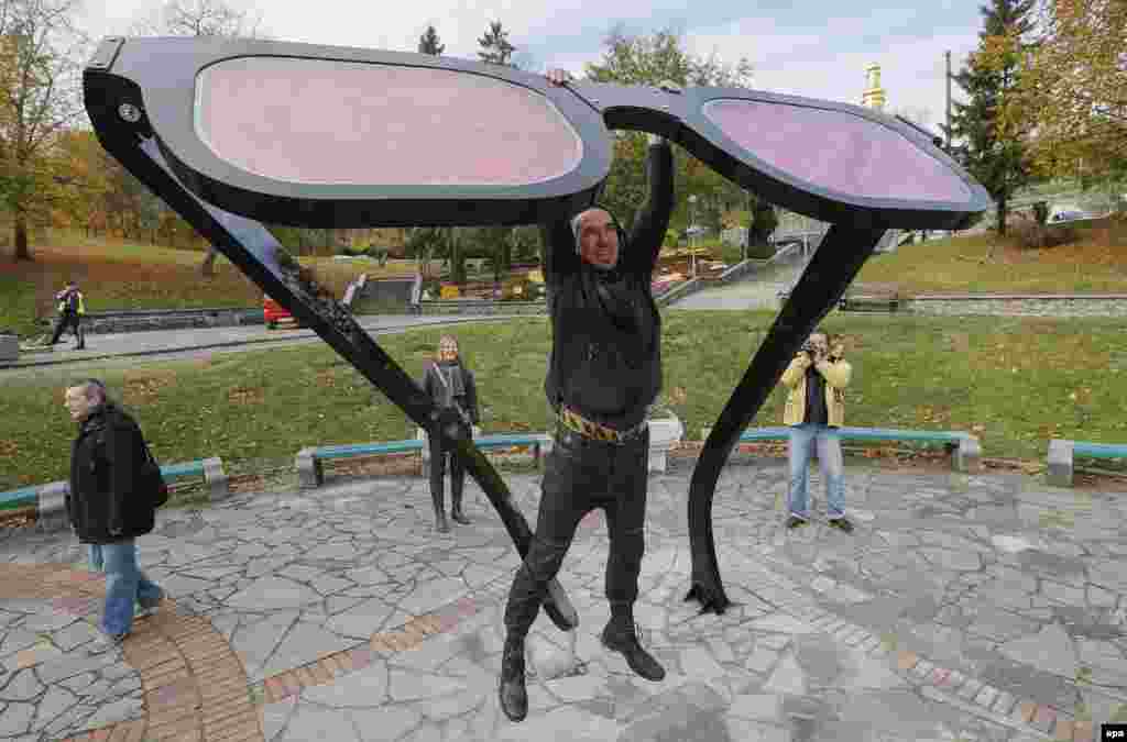 Ukrainian artist Volodymyr Padun, one of creators of the giant pink glasses, hangs on his artwork in Kyiv. (epa/Serhiy&nbsp;Dolzhenko) 