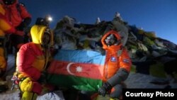 Участники экспедиции с развернутым азербайджанским флагом на вершине Эвереста. Справа - Мурад Ашурлы. Участок вершины за спиной альпинистов покрыт флагами и вымпелами. 19 мая 2013