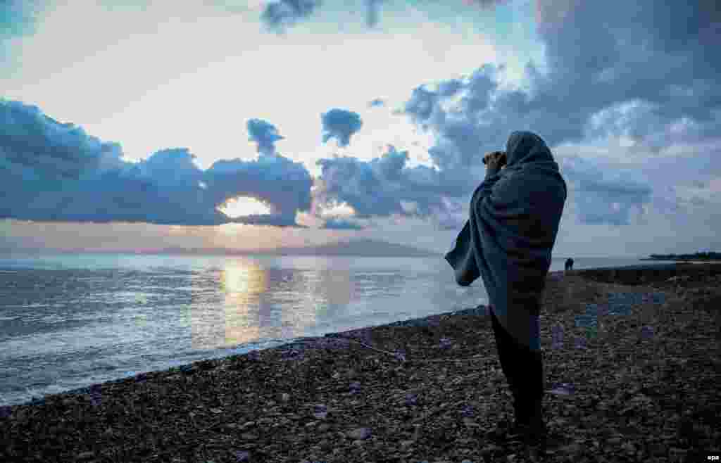 A volunteer looks out to sea through binoculars on a beach of the Greek island of Lesbos, near the port city of Mytilene. At least five people, including a baby, drowned in the Aegean Sea on March 10 when a speedboat sank trying to reach Lesbos from the Turkish coast. (epa/Kay Nietfeld)