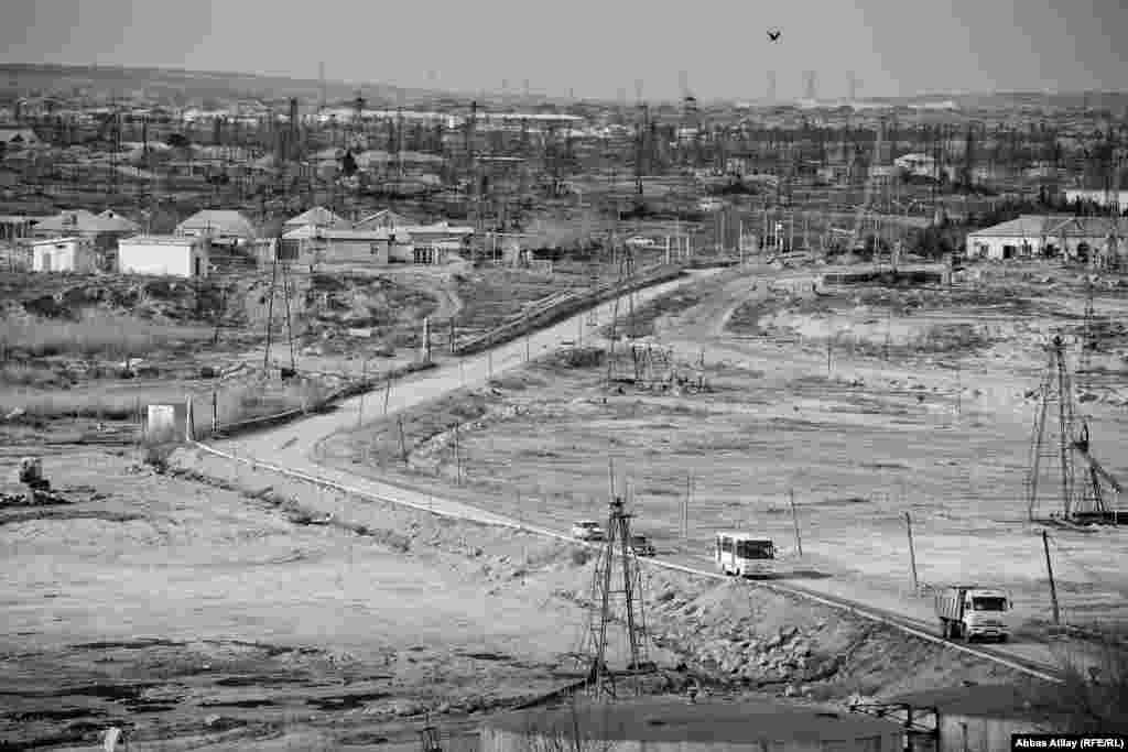 Neft buruqları arasından uzanan maşın yolu.