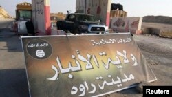 A banner is placed at a checkpoint belonging to the militant group Islamic State at the main entrance of Rawa on July 22, 2014.