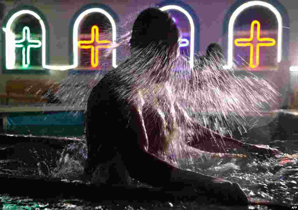 An Orthodox believer plunges into the waters of a portable pool set up outside a church in Simferopol, Crimea.