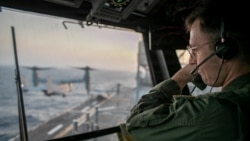 A naval officer aboard the USS Tripoli oversees flight operations in the Arabian Sea. 
