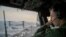 A naval officer aboard the USS Tripoli oversees flight operations in the Arabian Sea. 