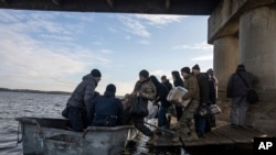 Из-за разрушения моста через Северский Донец в поселке Старый Салтов Харьковской области люди переправляются через реку на лодке. 29 декабря 2022 года