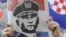 In Zagreb, a woman holds a newspaper with a portrait of General Ante Gotovina over the word "hero" as she watches the verdict in The Hague.