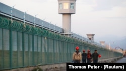 Workers walk by the perimeter fence of what is officially known as a vocational-skills education center in Dabancheng in China's Xinjiang Uyghur Autonomous Region in 2018.