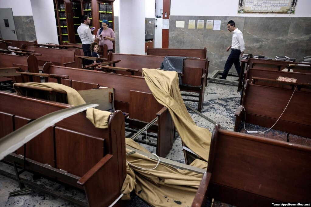 Njerëz duke shikuar një shkollë të dëmtuar fetare pas një sulmi iranian në Izraelin qendror, më 16 qershor.