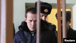 Former opposition campaigner Vasil Parfyankau is escorted by policemen into court in Minsk on February 17.